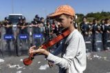 Emocionante: Refugiado sírio toca violino em frente a barricada policial