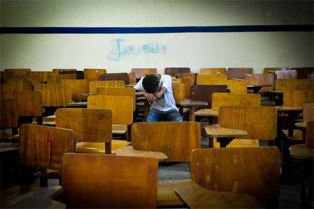sala de aula aluno sozinho em sala com cabeça baixa